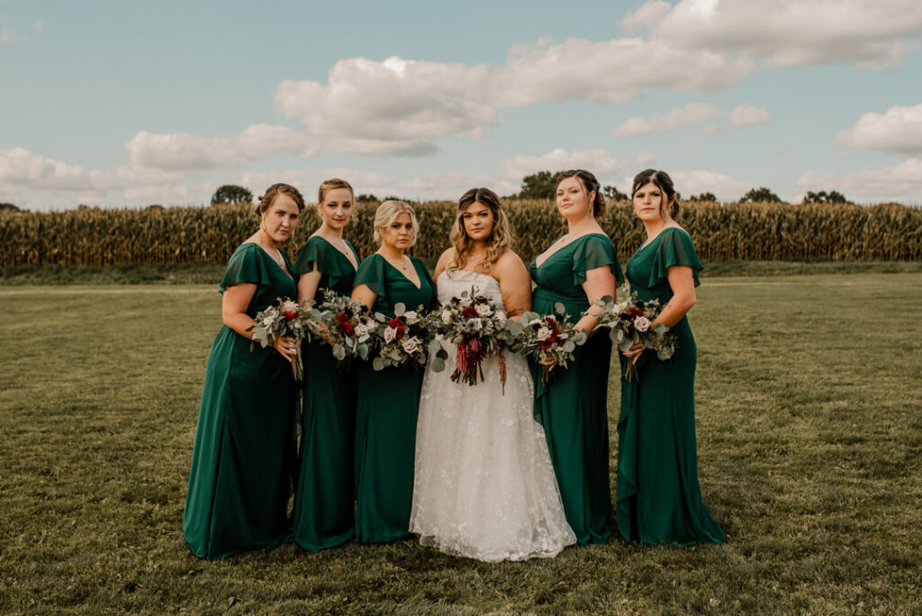 Bride and her bridesmaids in their dresses, looking straight faced at the camera. 