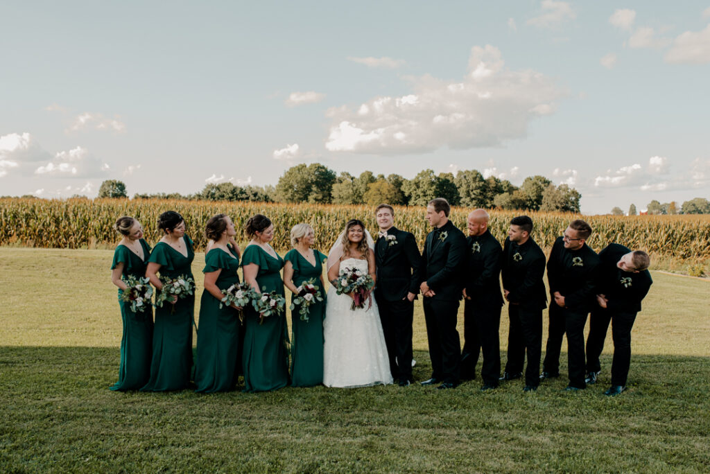 Fully bridal party after ceremony. All looking at the bride and groom. Bride and groom are smiling at camera. 