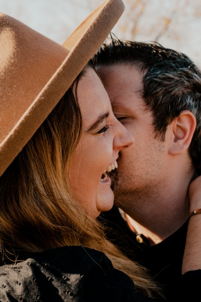 Close up of man and woman's faces. He is kissing her cheek 