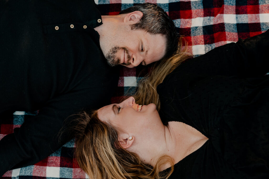 Man and woman, both laying on their backs, looking at each other. Shoot from above. 